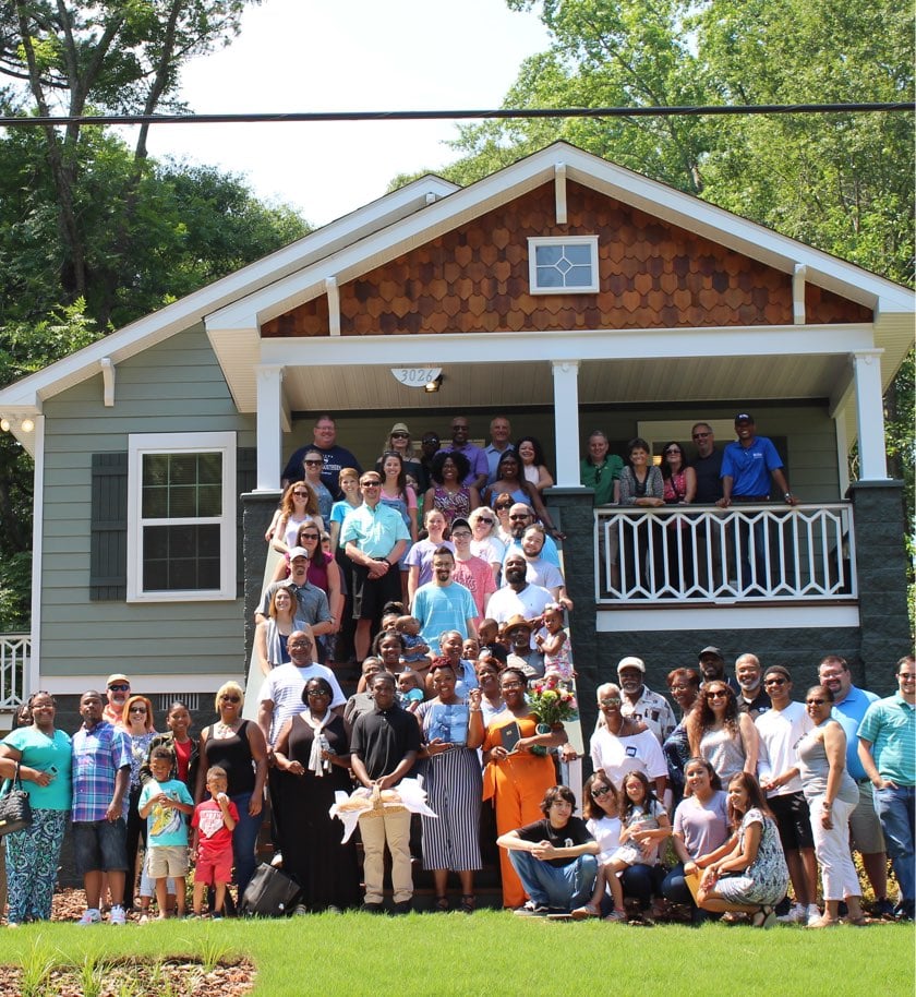 CRH employees support community events, posing with community members in front of a house